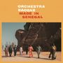 "Orchestra Baobab Made in Senegal" steht oben in großer Schrift. Mehrere Personen gehen vor einer massiven Statue.