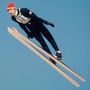 Die Zahl 58 auf einem Skispringer, der in der Luft schwebt. Der Himmel ist klar und blau.