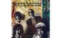 "TRAVELING WILBURYS" in großer Schrift. Vier Männer mit Sonnenbrillen, vor einem abstrakten, erdfarbenen Hintergrund.