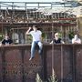 Text: "Dylan Lana Hotel Nº5". Vier junge Männer sitzen auf einem rostigen Industriebau.