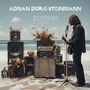 ADNAN ĐURIĆ-STEINMANN, ZEITGEIST. Gitarrist am Strand mit Verstärkern geschmückt mit Blumen, Mikrofon im Vordergrund.