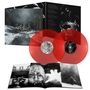 Zwei rote Vinyl-Schallplatten, ein Buch mit Schwarz-Weiß-Fotografien und ein Plattencover mit winterlicher Walddarstellung.