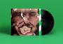 Ein schwarzes Vinyl vor einem Cover mit einem verzerrten Gesicht auf grünem Hintergrund.