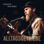 Texte: "Lennon von Seht" und "ALLTAGSGETRIEBE".  
Ein bärtiger Mann mit Gitarre und Mütze singt in ein Mikrofon.