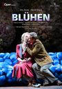 "BLÜHEN" wird groß gezeigt. Paar sitzt auf blauen Kissen, Mann küsst Frau liebevoll. Oper Frankfurt Logo oben links.