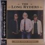 "The Long Ryders", "High Noon Hymns". Drei Männer, zwei mit Sonnenbrillen, der mittlere im Anzug vor einem dunklen Hintergrund.