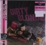 "Dirty Blonde", "New Religion". Frau in auffälliger Kleidung auf einem Sofa, umgeben von Metallgittern.