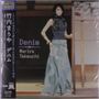 "Denim Mariya Takeuchi" steht auf Englisch geschrieben. Eine Frau trägt ein langes, blaues Kleid in traditionellem Umfeld.