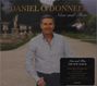 "Daniel O'Donnell Now and Then" Albumcover mit einem Mann in hellem Hemd auf einem Gartenweg, umgeben von Statuen.