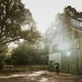 Text: „Jason McNiff Dust of Yesterday“. Eine Person steht mit Gitarre vor einer alten Scheune im Sonnenlicht.