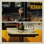 "Danny George Wilson" und "ARCADE" sind zentral sichtbar. Szene in einem Café, Mann neben einem Tisch mit Gewürzen, gelbes Interieur.