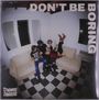 Texte: "DON'T BE BORING", "DYNAMITE SHAKERS". Vier Personen auf hellem Sofa, scherzend. Raum mit kariertem Boden.