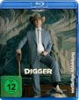 "DIGGER", "FSK ab 12 freigegeben". Ein Mann im Anzug und Cowboyhut steht mit einem Fuß auf einem Globus, hinter ihm eine Wandmalerei.