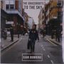 "The Grassroots to the Sky" und "Cian Downing". Eine Person läuft in einer städtischen Straße mit Gebäuden und Passanten.