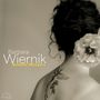 Texte: "Barbara Wiernik, Between Whispers". Frau mit Tattoo und großer Blume im Haar, sepiafarben.