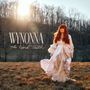 "WYNONNA The Hard Truth." Eine Frau in einem langen, fließenden Kleid mit roten Haaren steht in einer herbstlichen Landschaft.