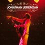 Text: "JONATHAN JEREMIAH LIVE AT ROYAL THEATRE CARRÉ". Ein Musiker mit Gitarre auf einer rot beleuchteten Bühne.