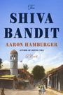 "The Shiva Bandit" von Aaron Hamburger. Eine Straßenszene mit alten Gebäuden und einem Turm in malerischer Umgebung.