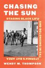 CHASING THE SUN. Fünf Männer stehen locker auf einem Gehweg vor Geschäften. Orange Hintergrund mit weißem Text.