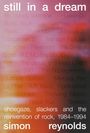 Text: „still in a dream“, gefolgt von vielen Bandnamen. Untertitel beschreibt Musikrichtungen und Jahre. Autor: Simon Reynolds. Hintergrund in unscharfen Rot-, Rosa- und Orangetönen.