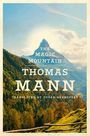 "THE MAGIC MOUNTAIN, THOMAS MANN, TRANSLATED BY SUSAN BERNOFSKY" vor einer Berglandschaft mit blauem Himmel und Wäldern.