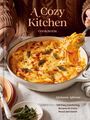 "A Cozy Kitchen Cookbook" Text. Frau im Strickpullover hält Auflauf; Teller und Salbei als Dekoration.