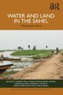 "Water and Land in the Sahel: Mapping the Flow." Ufer mit Menschen und Booten, Palmen im Hintergrund.