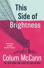 Aufschrift: "This Side of Brightness" von Colum McCann. Illustration einer Brücke vor einer Skyline, in Rot und Blau.