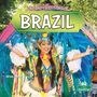 "LIFE AND TRADITIONS IN BRAZIL". Eine Frau im bunten Federkostüm beim Tanzen. Lebhafte Farben und festliche Atmosphäre.