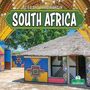 „Life and Traditions in South Africa“. Strohdachhaus mit farbenfrohen Mustern umgeben von grünen Bäumen.