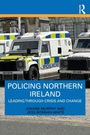 "Policing Northern Ireland: Leading Through Crisis and Change" von Joanne Murphy und Jess Bonnan-White. Polizei-Fahrzeuge auf Straße.