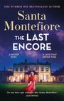 "Santa Montefiore - The Last Encore. Eine Frau im roten Kleid steht vor einem beleuchteten Herrenhaus unter einem sternklaren Himmel."