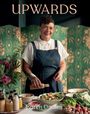 "UPWARDS", "Karen Dudley". Eine Frau in Schürze, vorbereitet Essen vor Blumen und Gemüse, lächelnd vor einem grünen Paravent.