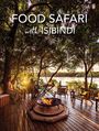 "Food Safari with Isibindi"; Holzboden, Feuerstelle, Menschen sitzend, üppige Bäume, Fluss im Hintergrund, entspannte Atmosphäre.