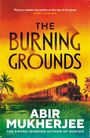 Text in der Mitte: "THE BURNING GROUNDS". Unten: "ABIR MUKHERJEE". Dampflokomotive fährt durch tropische Landschaft.