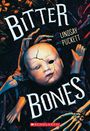 "Bitter Bones" und "Lindsay Puckett". Ein Puppenkopf mit Rissen, gehalten von Skelettarmen, auf dunklem Hintergrund.