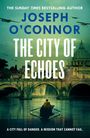 „The City of Echoes“ von Joseph O’Connor. Boot auf einem Fluss, dahinter eine historische Stadt mit Brücke und Dom.