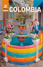 Text: "COLOMBIA", "Rough Guides", "Free eBook". Bunter Brunnen mit Figuren in traditioneller Kleidung in einer farbenfrohen Gasse.