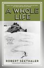 „A Whole Life“ von Robert Seethaler. Schwarz-weißes Foto eines Skifahrers auf einer verschneiten Berglandschaft.