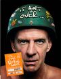 Ein Mann trägt einen Helm mit dem Text "IT AIN'T OVER..." und Aufklebern, daneben ein orangefarbenes Plakat mit weißem Text.