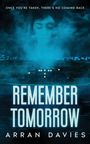 Text: "ONCE YOU’RE TAKEN, THERE’S NO COMING BACK", "REMEMBER TOMORROW", "ARRAN DAVIES". Gesicht in Wolken über einer düsteren Stadt.