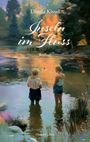 Text: "Ursula Kissel, Inseln im Fluss, Roman". Zwei Frauen stehen im Wasser eines malerischen Flusses bei Sonnenuntergang.