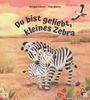 Titel: "Du bist geliebt, kleines Zebra". Illustration von zwei sich umarmenden Zebras in einer Wüstenlandschaft. Ein Vogel fliegt am Himmel.