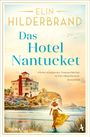 „Das Hotel Nantucket“ von Elin Hilderbrand. Eine Frau im Sommerkleid geht am Wasser, daneben ein malerisches Haus.