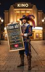 "Film ab! Ein fantastisches Filmbuch von Sabine und Thomas Benda. Kino im Hintergrund, Mann in Musketierkostüm mit Federhut."
