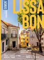 Große gelbe Schrift: "LISSABON". Kopfsteinpflasterstraße, bunte alte Gebäude, Bäume, mediterranes Flair.