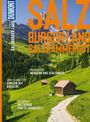 „SALZBURGER LAND SALZKAMMERGUT“, idyllische Almlandschaft mit grünen Wiesen, Hütten und Bergen im Hintergrund.