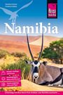"Namibia" in großen Buchstaben, darunter eine liegende Antilope vor einer Wüstenlandschaft mit Bäumen und Dünen.