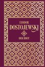 “Fjodor Dostojewski, Der Idiot” in goldener Schrift, ornamental verziert auf rotbraunem Hintergrund.