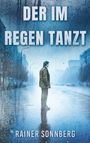 „DER IM REGEN TANZT“, „RAINER SONNBERG“. Ein Mann steht auf einer regnerischen, leeren Straße in blauem Licht.